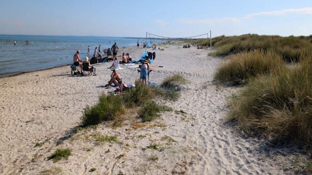 A sandy beach with people relaxing and a volleyball net in the distance. - 6 Person Holiday Home in Albaek (Aalbaek)
