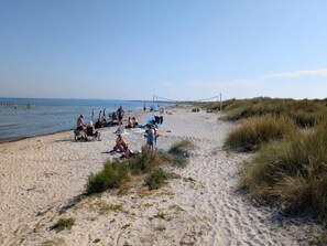 A sandy beach with people relaxing and a volleyball net in the distance. - 6 Person Holiday Home in Albaek (Aalbaek)