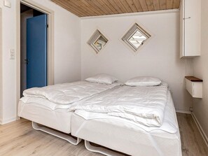 A single-bed room with a wooden ceiling, a blue door, and a white wall with two diamond-shaped mirrors. - 6 Person Holiday Home in Albaek (Aalbaek)