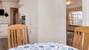A kitchen with white cabinets, a built-in oven, and a dining area with a table and chairs. - 6 Person Holiday Home in Albaek (Aalbaek)