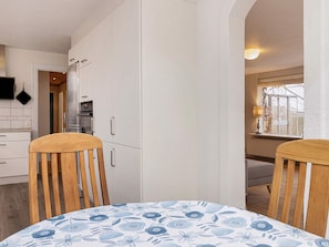 A kitchen with white cabinets, a built-in oven, and a dining area with a table and chairs. - 6 Person Holiday Home in Albaek (Aalbaek)