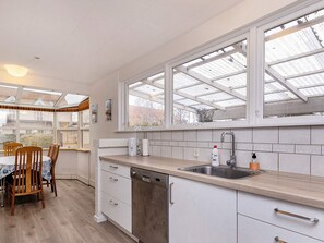A modern kitchen with a dishwasher, a sink, and a window with a metal frame. - 6 Person Holiday Home in Albaek (Aalbaek)