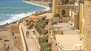 A coastal promenade with a lighthouse, beach, and stone buildings. - Villa in Spain Near Stunning Beaches (Roquetas de Mar)