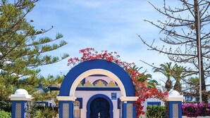 A hotel entrance with a blue archway, a fountain, and a sign with 'AT' and 'J'. - Villa in Spain Near Stunning Beaches (Roquetas de Mar)