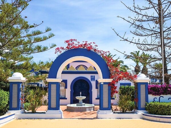 A hotel entrance with a blue archway, a fountain, and a sign with 'AT' and 'J'.