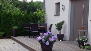 Eine Terrasse mit Holzdeck, Gartenmöbeln und Blumentöpfen.