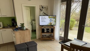 Eine moderne Küche mit Essbereich, einem an der Wand befestigten Fernseher und Blick ins Freie.