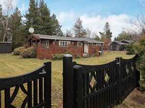 A wooden cabin with a fenced yard, satellite dish, and a small shed. - 6 Person Holiday Home in Vaeggerlose (Vaeggerlose)