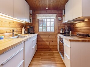 A compact kitchen with wooden walls, a window with a view, and basic amenities.