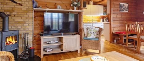 Un acogedor interior de cabaña con chimenea, televisor, comedor y cocina.