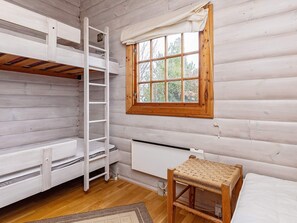 A room with a bunk bed, a ladder, a window with a view of trees, a radiator, and a woven chair. - 6 Person Holiday Home in Vaeggerlose (Vaeggerlose)