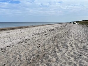 A sandy beach with a vehicle parked on the right side. - 6 Person Holiday Home in Vaeggerlose (Vaeggerlose)