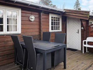 A wooden cabin with a dining table and chairs, a white door, and a window with a curtain. - 6 Person Holiday Home in Vaeggerlose (Vaeggerlose)