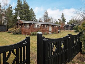 A wooden cabin with a fenced yard, a satellite dish, and a small shed. - 6 Person Holiday Home in Vaeggerlose (Vaeggerlose)