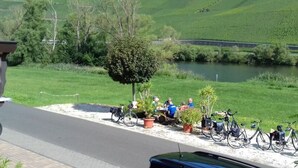 Un espace extérieur aménagé, offrant un cadre agréable avec vue sur une rivière et des collines, agrémenté de vélos et de plantes en pot.