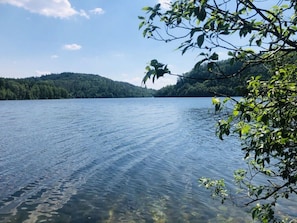Un lago tranquilo de aguas transparentes, rodeado de colinas boscosas.