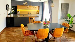 A modern kitchen with a central island, pendant lighting, and a dining area with orange chairs. - Villa Calypso Royal Apartment (Zadar)