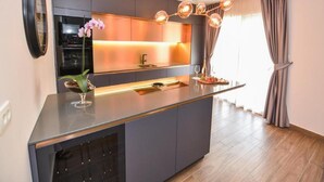 A modern kitchen with a central island, built-in appliances, and a pendant light. - Villa Calypso Royal Apartment (Zadar)