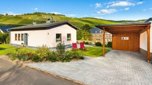 A two-story building with a small garden and a paved driveway. - Holiday Home Moselle Valley (Maring-Noviand)