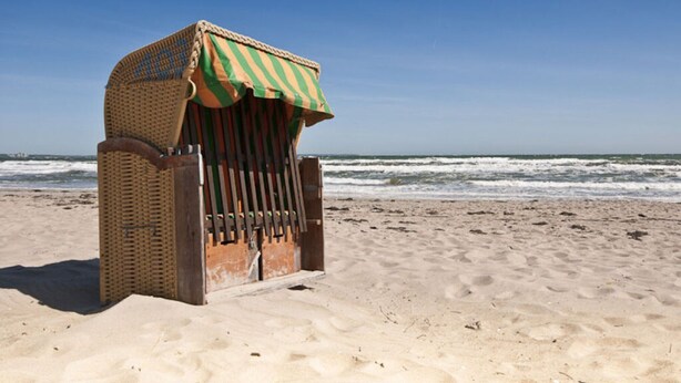 A beach chair with a striped canopy on a sandy beach. - Deck 4 Modern Retreat (Timmendorfer Strand)