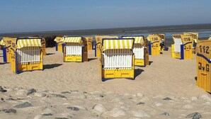 Beach huts with numbers on them, arranged in rows on a sandy beach. - Holiday Home Heimathafen Am Ringwall (Cuxhaven)