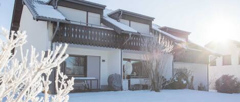 A two-story house with a snow-covered roof and a clear sky.