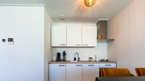 Moderni keittiö, jossa on valkoiset kaapit, puinen työtaso ja musta ruokapöytä.