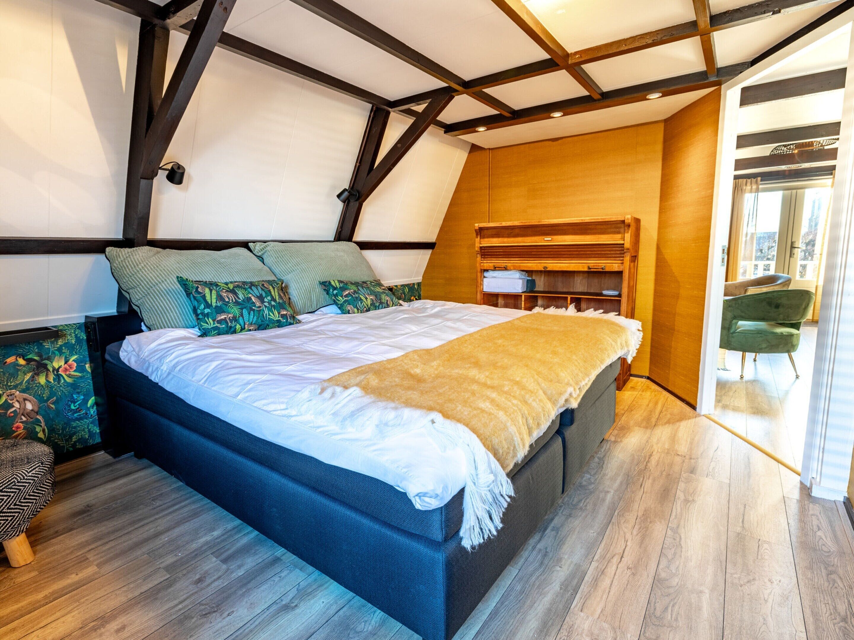 A bedroom with a bed, wooden headboard, and a view of the outside.