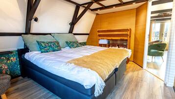 A bedroom with a bed, wooden headboard, and a view of the outside.