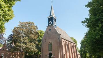 Een kerk met een klokkentoren, baksteenarchitectuur en een gazon ervoor.