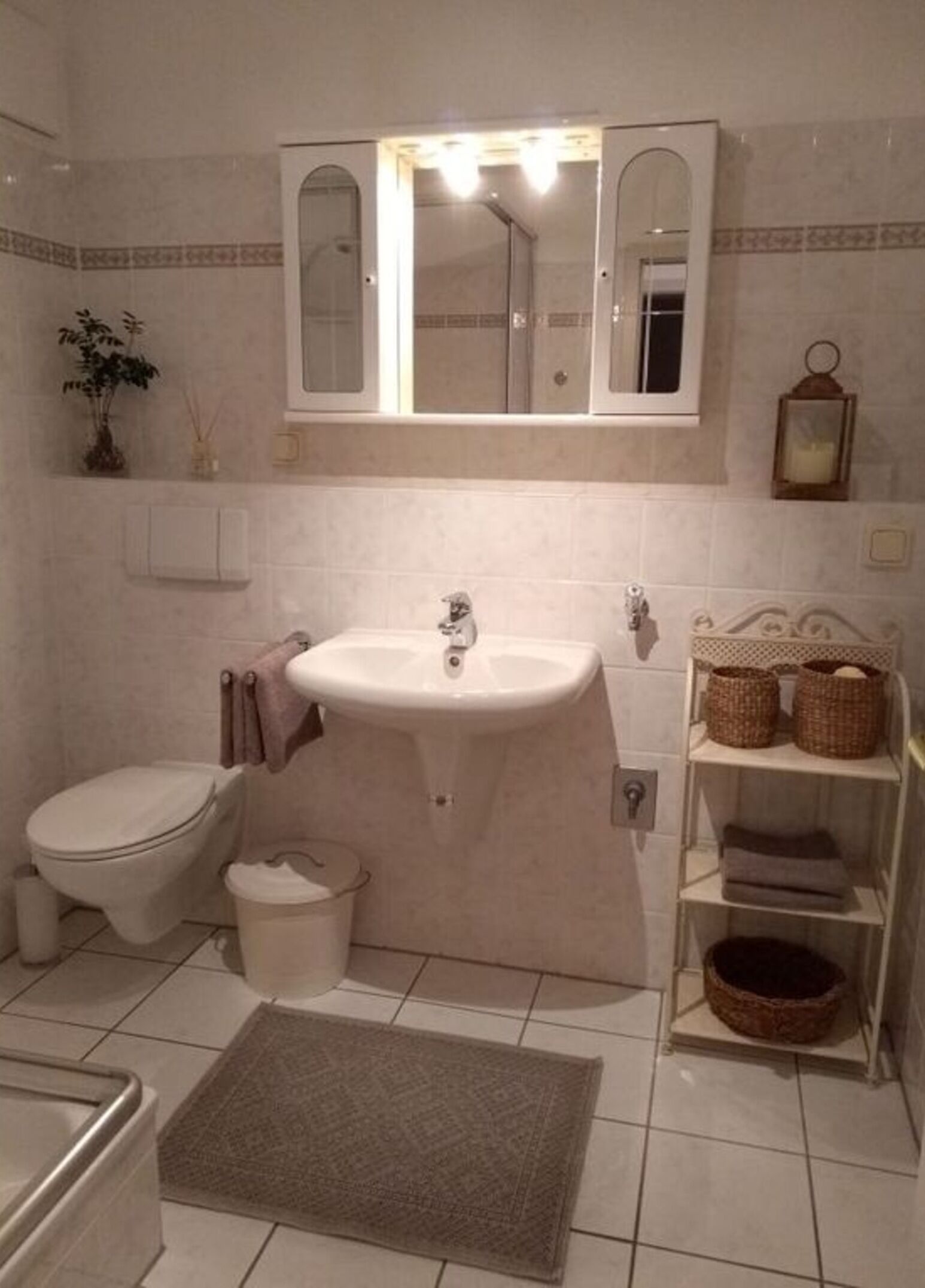 Une salle de bain avec un lavabo, des toilettes et une étagère avec des paniers.