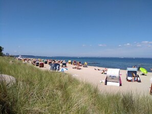A beach with numerous beach chairs and umbrellas, a few beach huts, and a clear view of the sea. - Holiday Apartment Baltic Sea Sweetheart (Timmendorfer Strand)