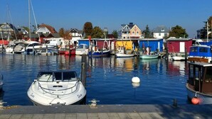 Un port de plaisance où sont amarrés différents types de bateaux, entouré de bâtiments aux couleurs vives.