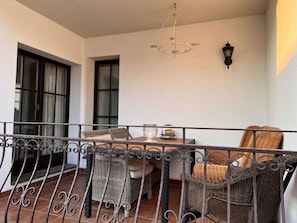A balcony with wicker furniture, a table, and a hanging light fixture.