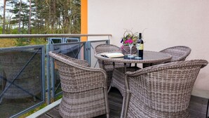 A balcony with wicker furniture, a table, and a bottle of wine. - Time out Karlshagen Comfortable Vacation Home (Karlshagen)