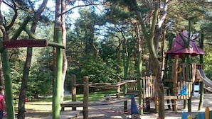 A playground with a wooden play structure, a slide, and a colorful fence. - Time out Karlshagen Comfortable Vacation Home (Karlshagen)