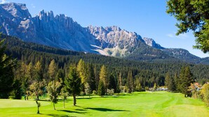 Un parcours de golf avec une chaîne de montagnes en arrière-plan.