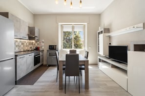 A modern kitchen with a dining area, built-in appliances, and a large window. - Holiday Home 'Appartamento Elegante Carbonia' with Balcony, Wi-Fi and Air Conditioning (Carbonia)