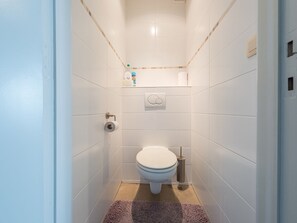 Une petite salle de bain moderne, avec des carreaux blancs, des toilettes, un bidet et un porte-serviettes.