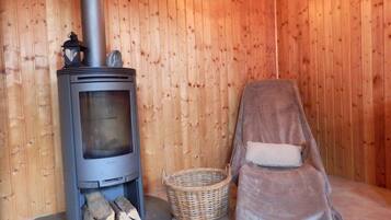 Cozy retreat with a wood-burning stove, comfortable chair, and plush blanket.