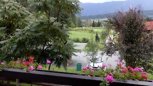 Un balcon donnant sur une rivière, entouré d’une végétation luxuriante et de plantes en fleurs.