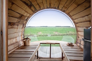 Un intérieur en bois avec une grande fenêtre en arc d’où l’on peut admirer un champ verdoyant.