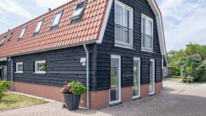 A modern two-story house with a sloped roof, large windows, and a brick foundation. - Holiday Home Near Forest With Wellness Garden (Den Burg)