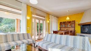 A cozy living room with two striped sofas, a glass coffee table, and a wooden dining table. - Holiday Home in Marciaga With Pool & Gulf Views (Costermano sul Garda)