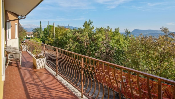 A balcony with a wrought iron railing, a brick floor, and a view of trees and mountains. - Holiday Home in Marciaga With Pool & Gulf Views (Costermano sul Garda)