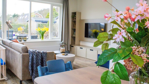 A modern living room with a sofa, chairs, a coffee table, and a TV. - Holiday Home in Noordwijk Near the Beach (Noordwijk)