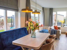 Una sala de estar moderna con una mesa de madera, un sofá azul y un jarrón de flores.