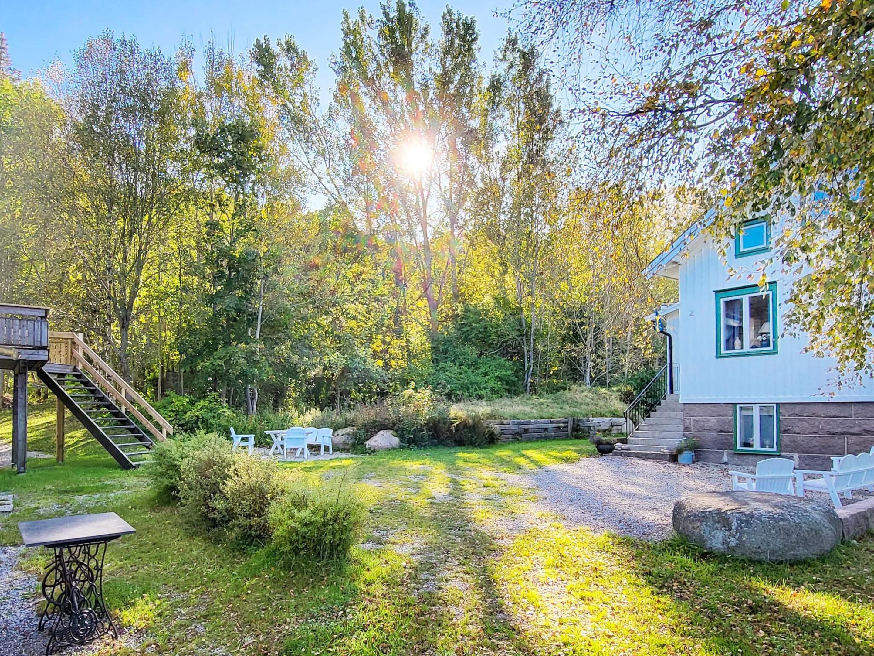 A house with a deck, a staircase, and a garden with a table and chairs.