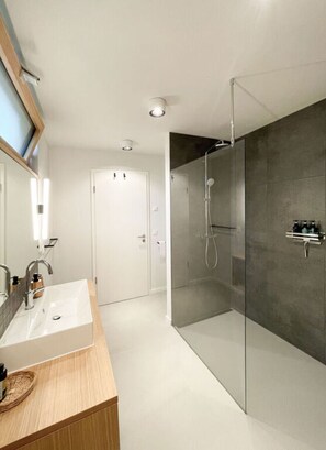 Une salle de bain moderne avec une douche à parois de verre, un meuble-lavabo en bois et un grand miroir.