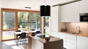 Eine moderne Küche mit weißen Schränken, einer Holz-Kochinsel und einem großen Fenster mit Blick auf einen Garten.